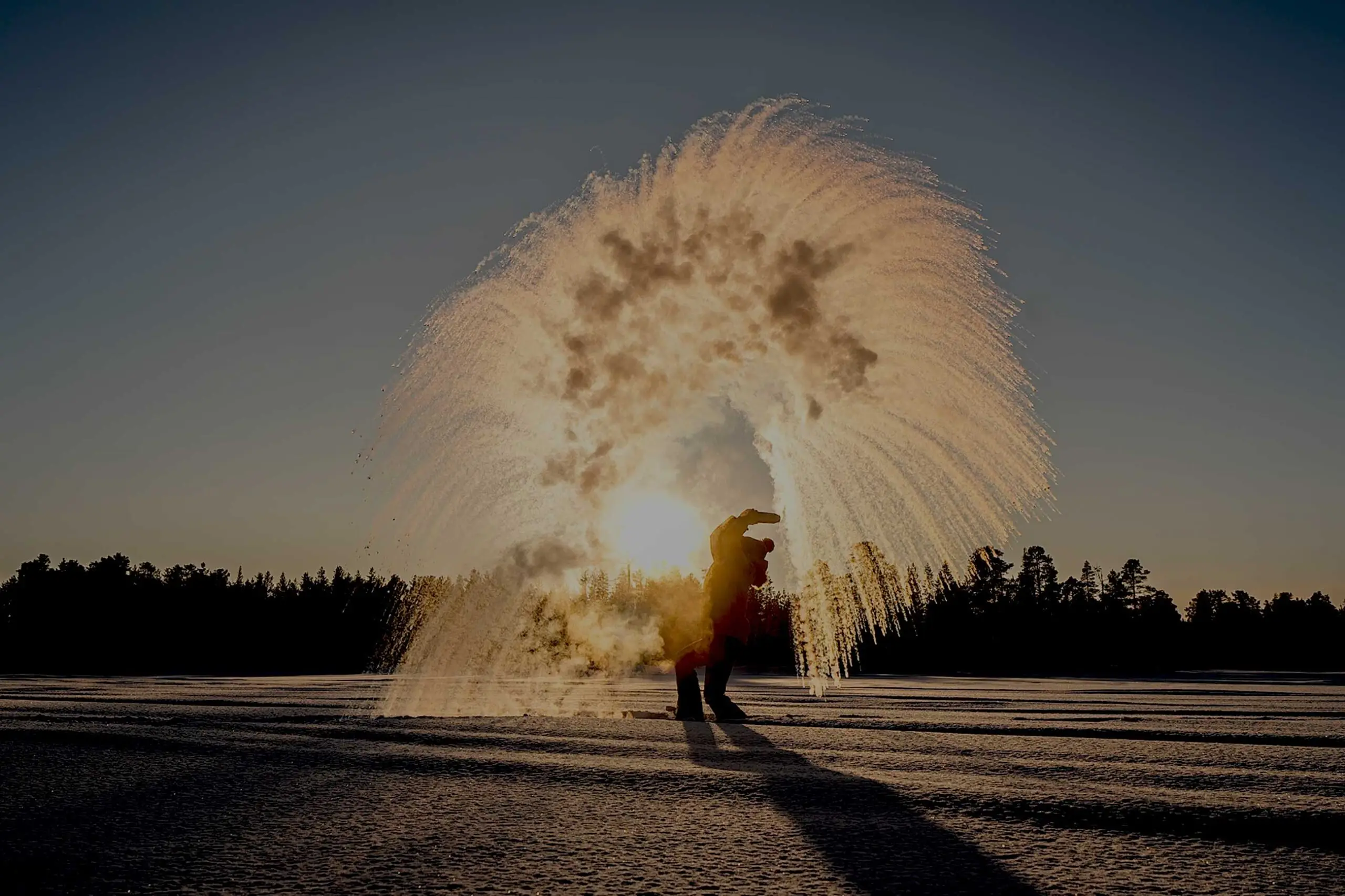 Boiling water thrown into the frozen air turns into a cloud of ice crystals at sunset