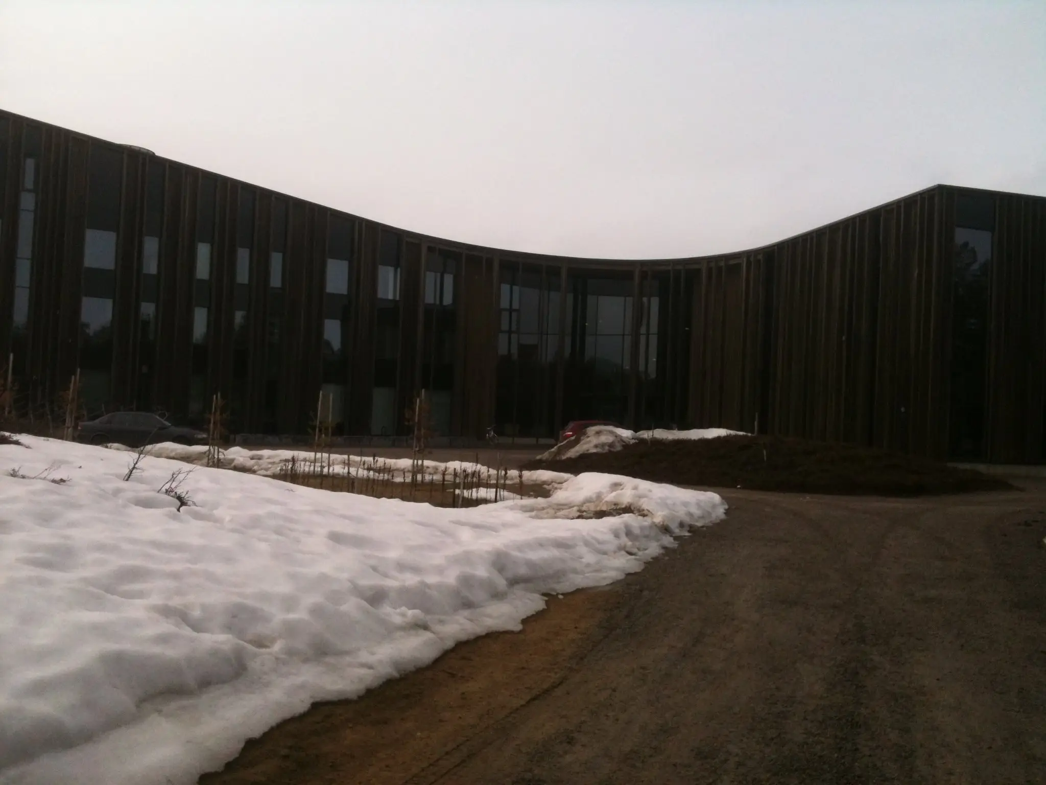 The curved wooden facade of Sajos, the Sami cultural centre in Inari, with snow on the ground