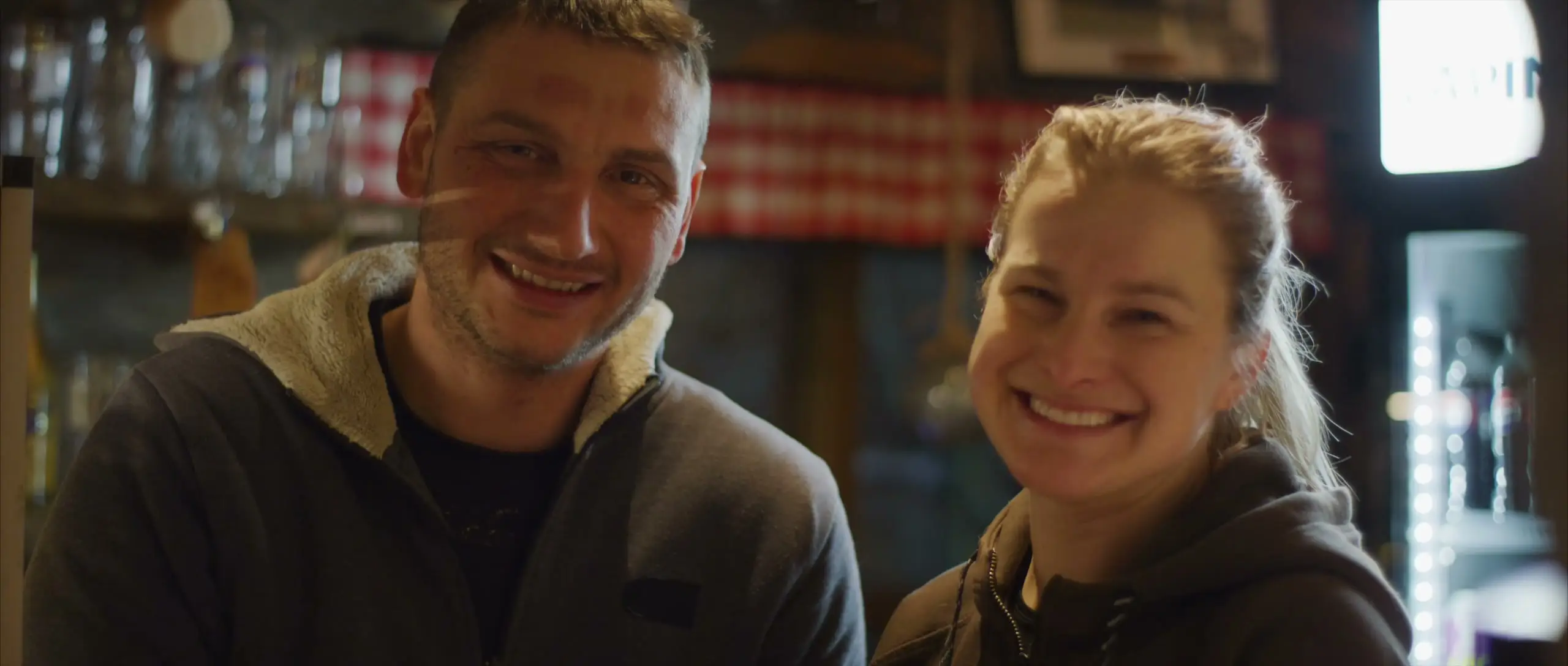 Kinga and Kevin smiling together at the bar of the log restaurant