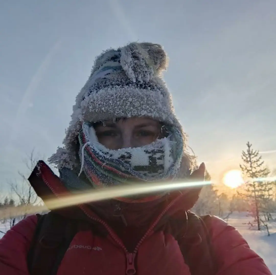 A guest with a frost-covered hat and scarf in the low winter sun